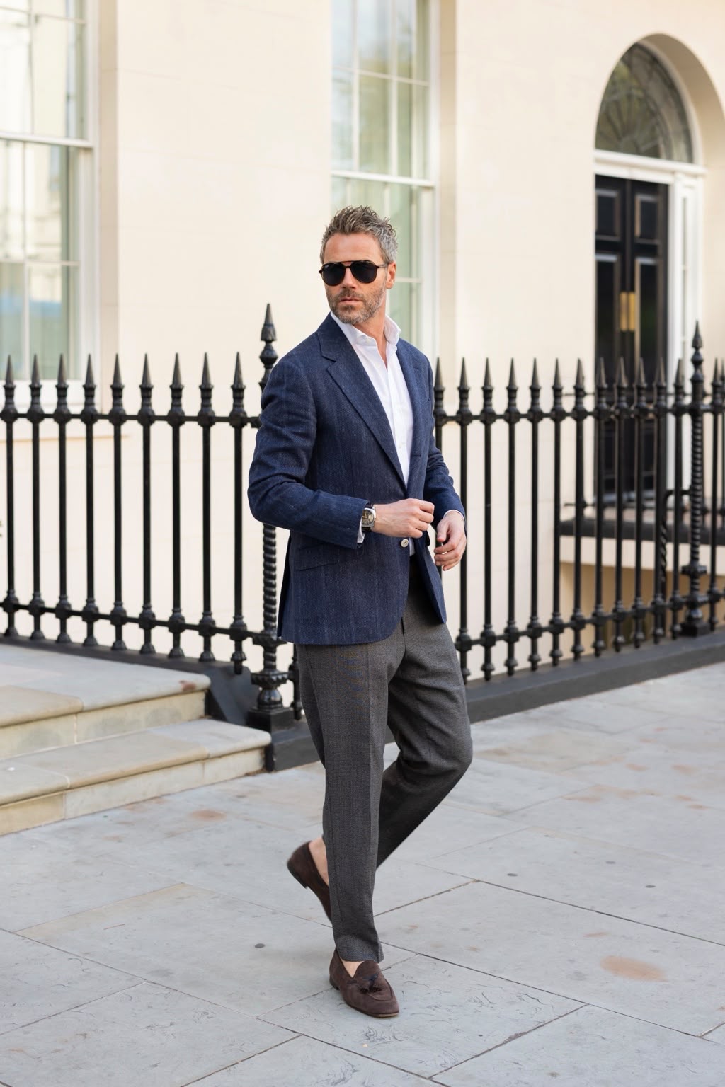 Gilberto Ramerini in a navy blazer and grey trousers, walking along a London pavement
