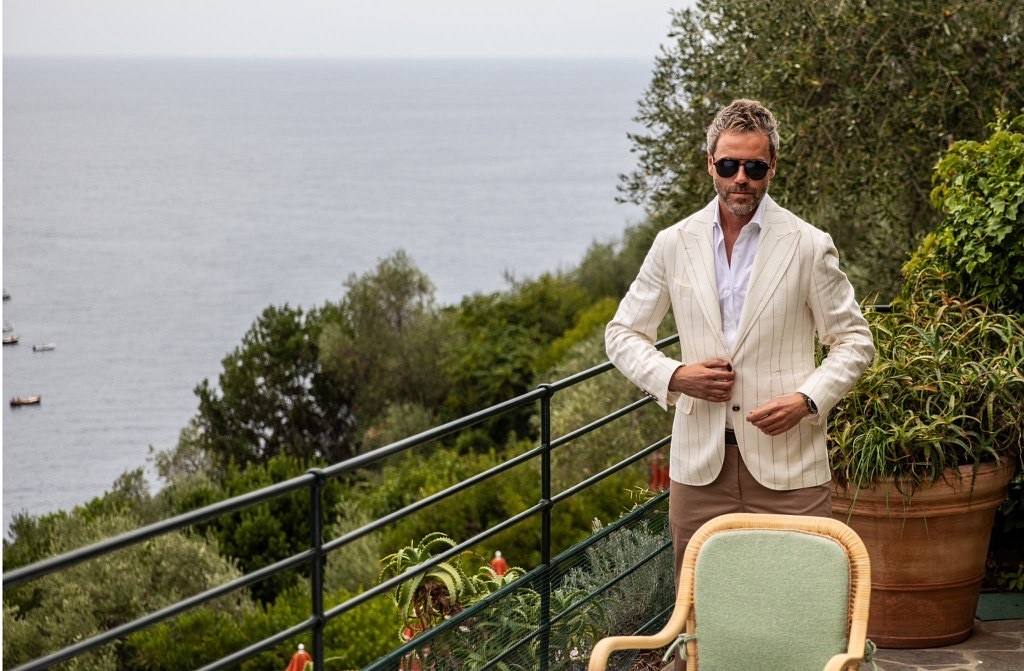 Gilberto Ramerini in a light blazer on a coastal terrace